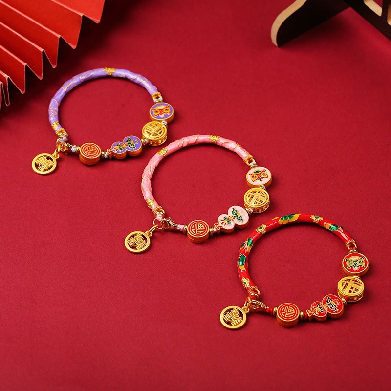 Armband – Glück & Wohlstand Energie mit goldenen Anhängern auf rotem Hintergrund.