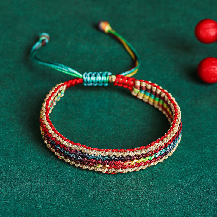 Tibetisches Armband Regenbogen bunt geflochten auf grünem Hintergrund Schutz