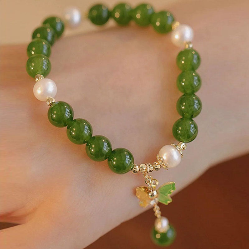 Grünes Armband mit Perlen und Schmetterling Charm am Handgelenk getragen elegant