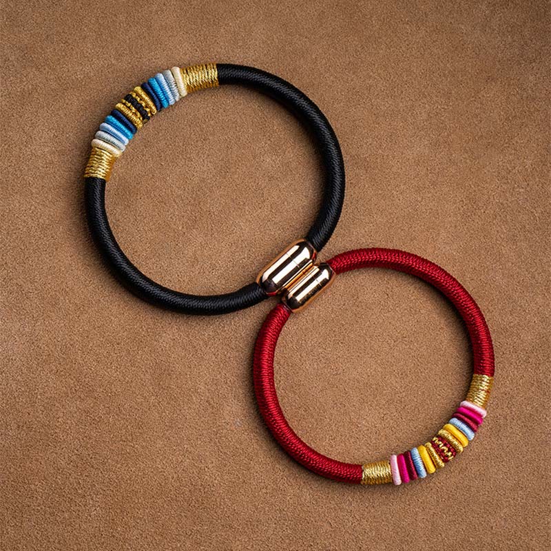 Magnetisches Armband mit schwarzem Stoff und farbigen Perlen elegant präsentiert.