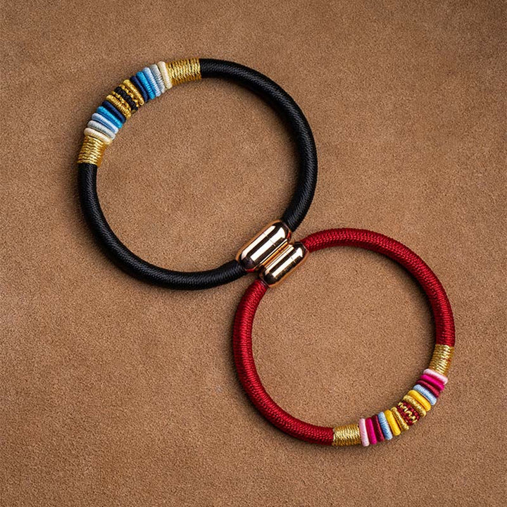 Magnetisches Armband mit schwarzem Stoff und farbigen Perlen elegant präsentiert.