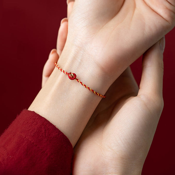 Rotes geflochtenes Armband mit Knoten-Anhänger am Handgelenk getragen