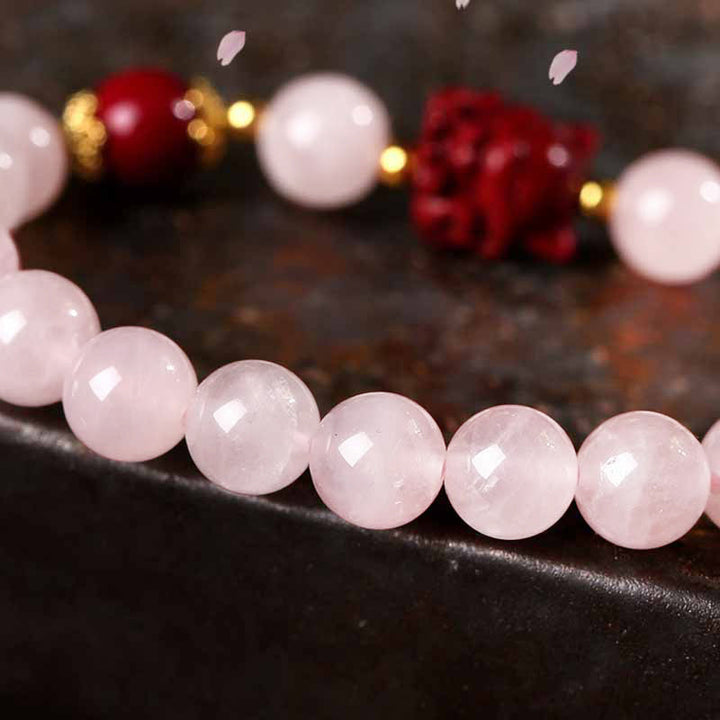 Rosenquarz Perlen Armband mit roten und goldenen Weihnachtsdekorationen elegant.