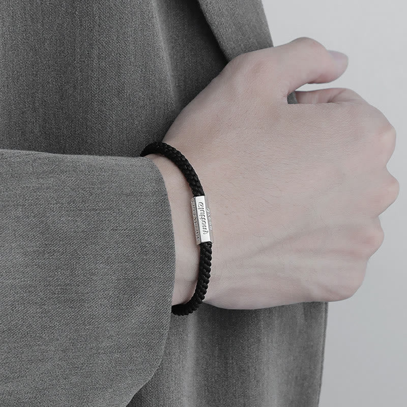 Schwarzes geflochtenes Armband mit Metallschild am Handgelenk getragen