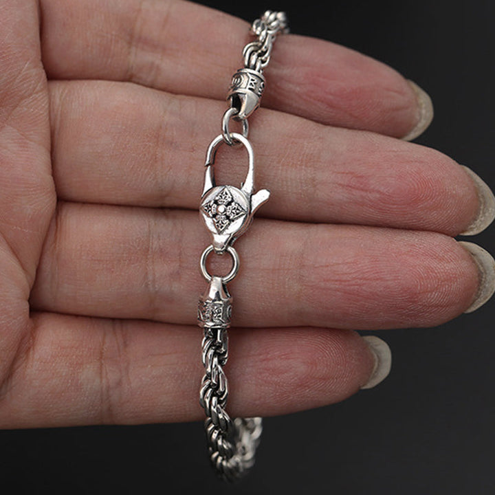 Silbernes Armband mit Om Mani Padme Hum Anhänger am Handgelenk getragen.