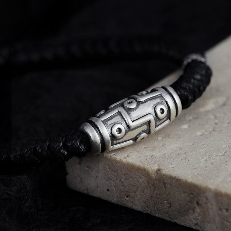 Silberarmband mit schwarzem Seil elegant auf Stein präsentiert