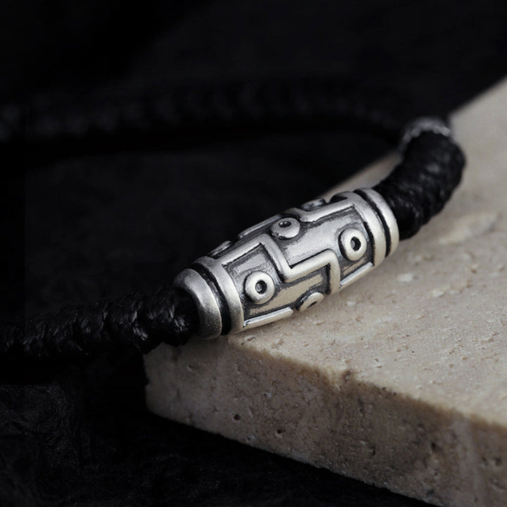 Silberarmband mit schwarzem Seil elegant auf Stein präsentiert