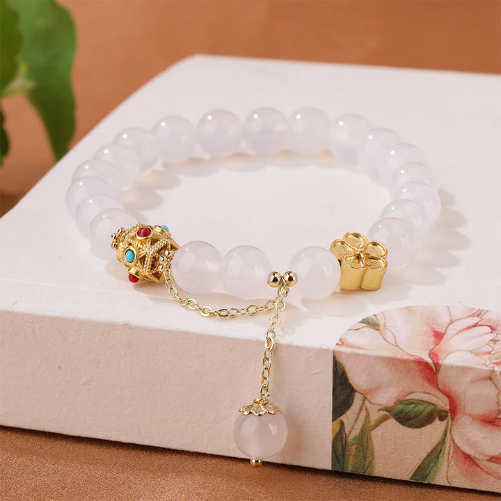 Weißes Quarz Armband mit goldenen Blüten Charms elegantes Design.