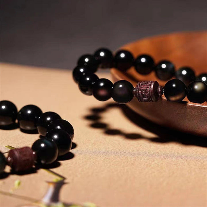 Schwarzes Obsidian Armband mit braunem Metallspacer elegant drapiert.