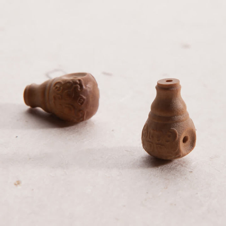 Zwei braune Sandelholz Mala Perlen mit Gravur auf heller Oberfläche.