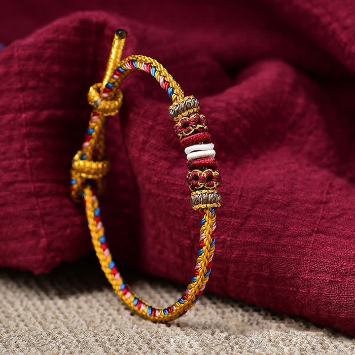 Geflochtenes rotes Schnur Karma Armband mit goldenen Perlen Nahaufnahme