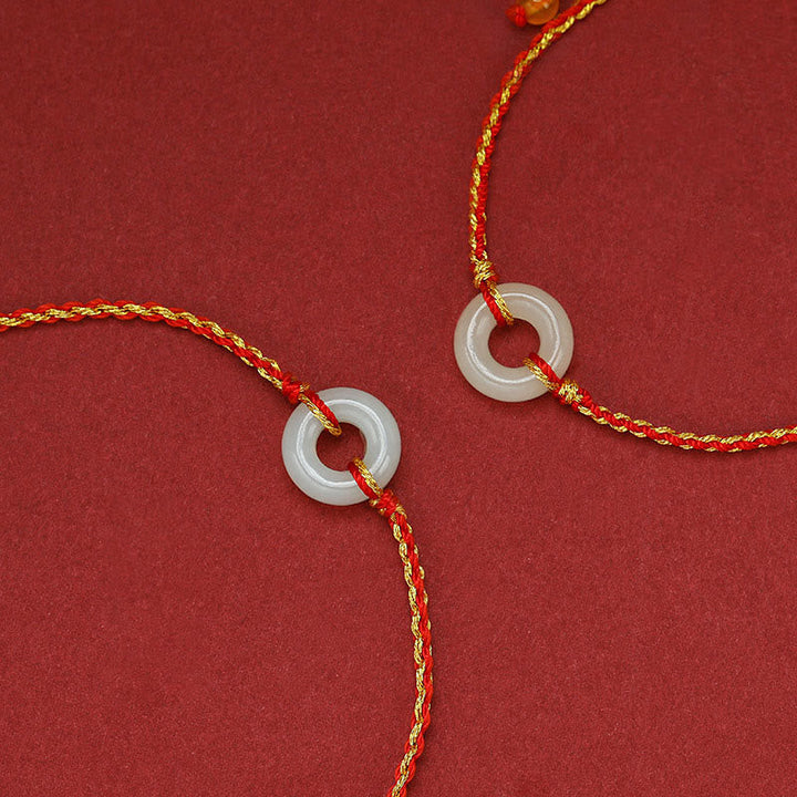 Jade Armband mit roter Kordel und Glückssymbolen elegant.