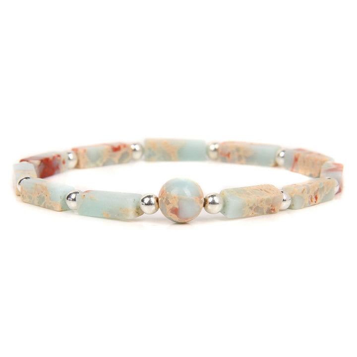 Elegantes Armband mit hellem Tigerauge und silbernen Perlen auf weißem Hintergrund