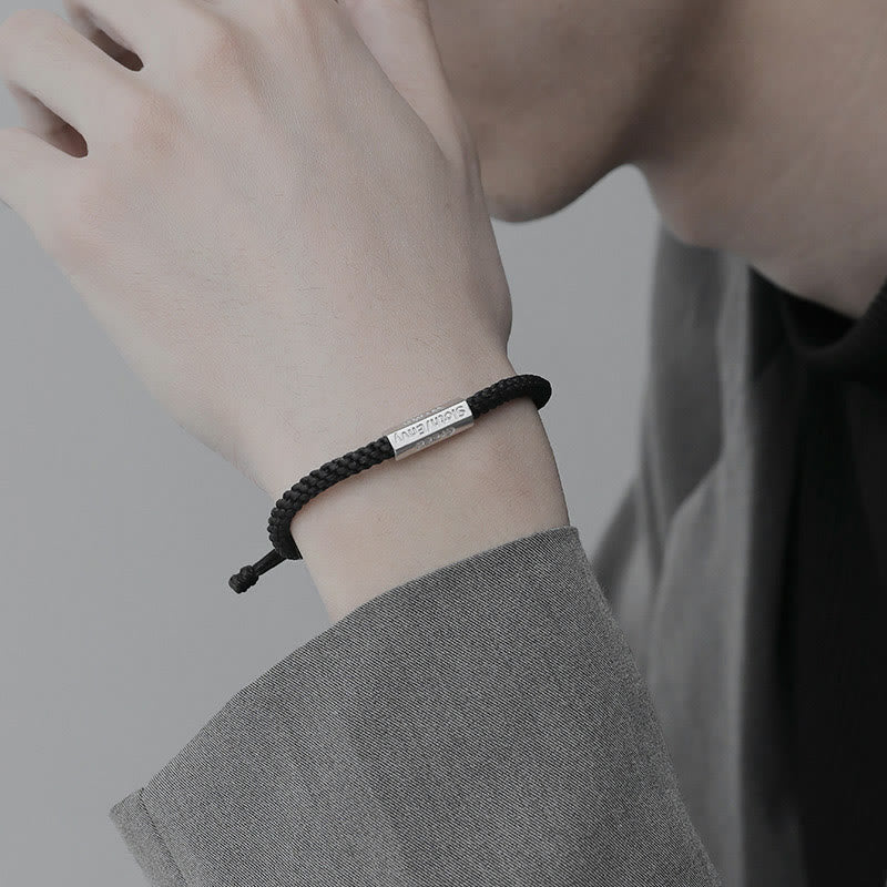 Schwarzes Armband mit Metallplakette am Handgelenk getragen Nahaufnahme