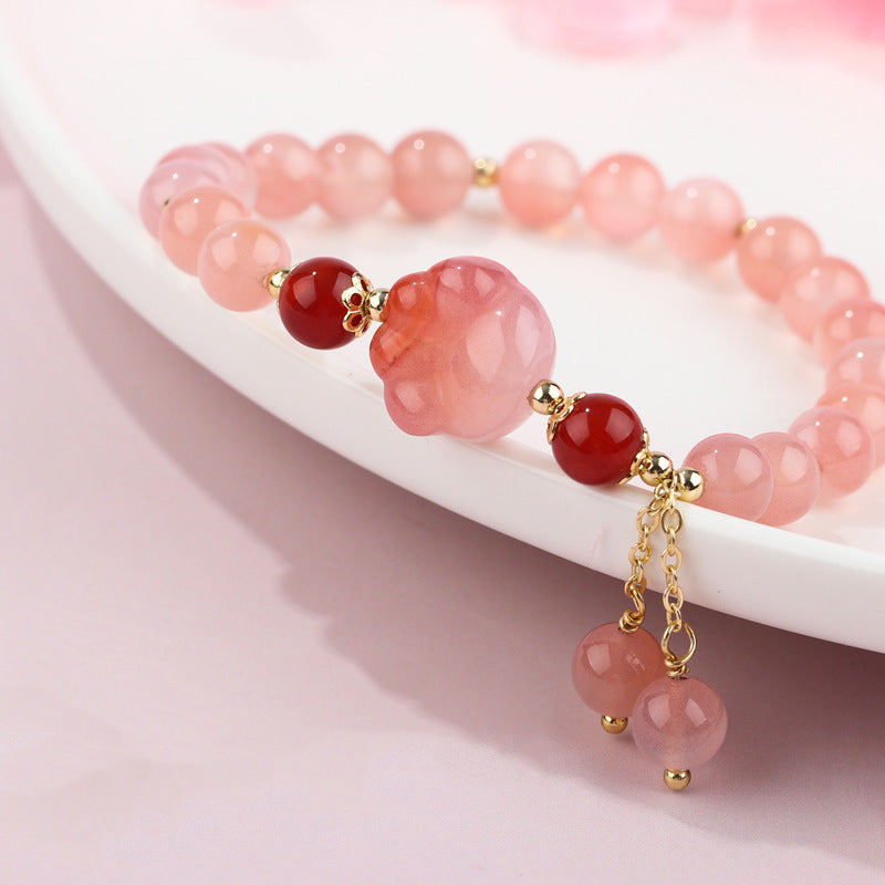 Rosafarbenes Achat Armband mit roten Steinen und Quasten Anhänger.