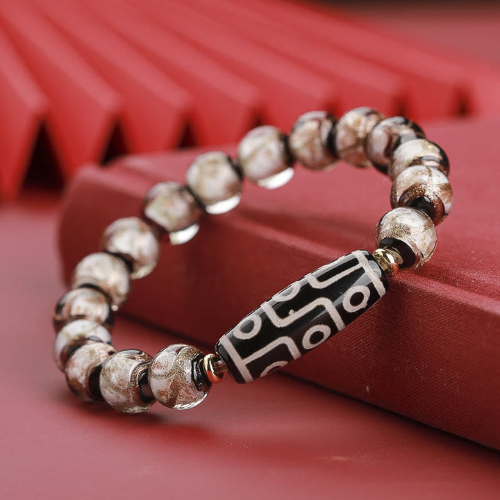 Armband – Wohlstand Balance mit silbernen Perlen und graviertem Mittelteil rosarosa Hintergrund.