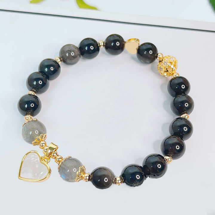 Schwarzes Obsidian Armband mit Silber Charm Herz elegant displayiert.