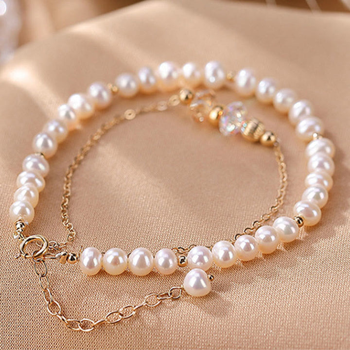 Elegantes Perlenarmband mit Kristallperlen und goldenem Verschluss getragen.