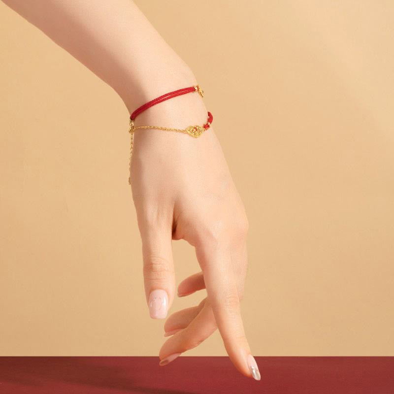 Rotes Seidenarmband mit goldenem Anhänger Glück Stärke Energie elegant getragen