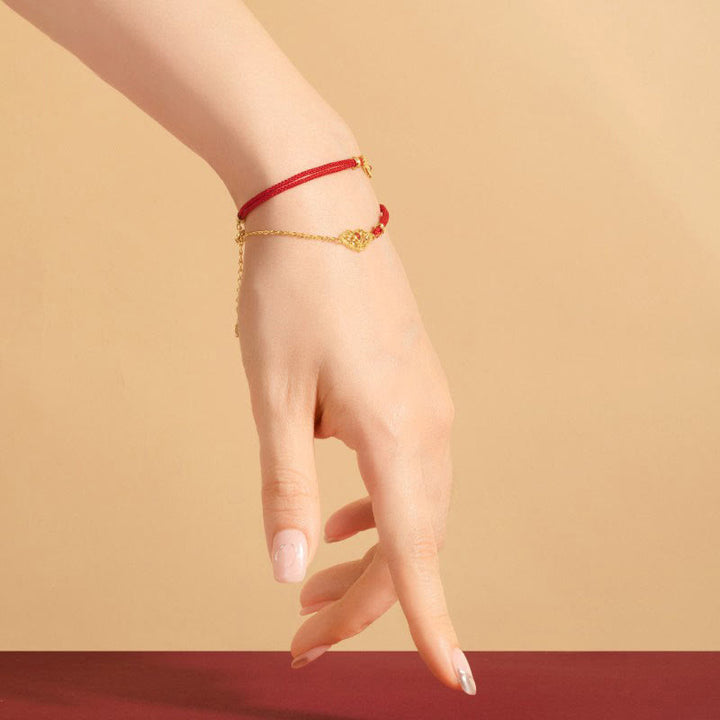Rotes Seidenarmband mit goldenem Anhänger Glück Stärke Energie elegant getragen