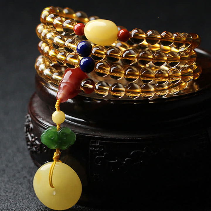 Mehrschichtiges Armband mit goldenem Citrin Anhänger und bunten Steinen.