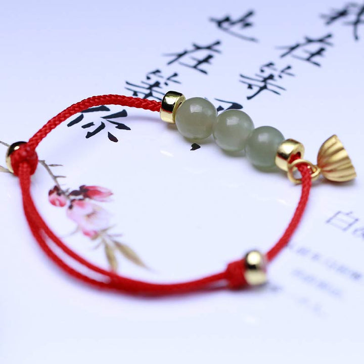 Jade Lotus Armband mit roten Schnur und goldenen Perlen getragen