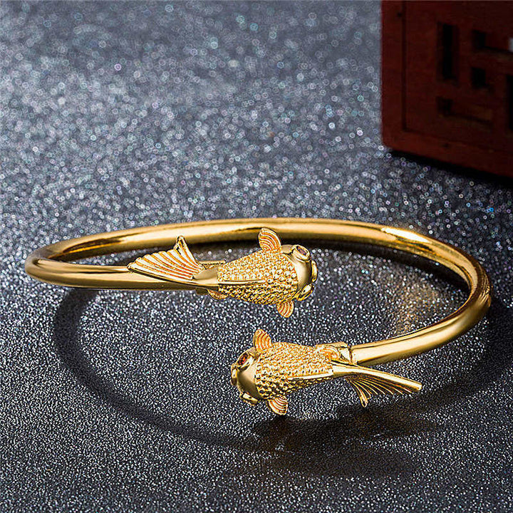 Goldenes Koi Fisch Armband Kupfer auf funkelndem grauem Hintergrund Schmuck