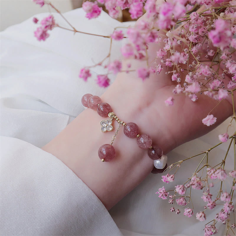Erdbeerquarz Perlen Armband mit Kleeblatt Charm elegant am Handgelenk getragen