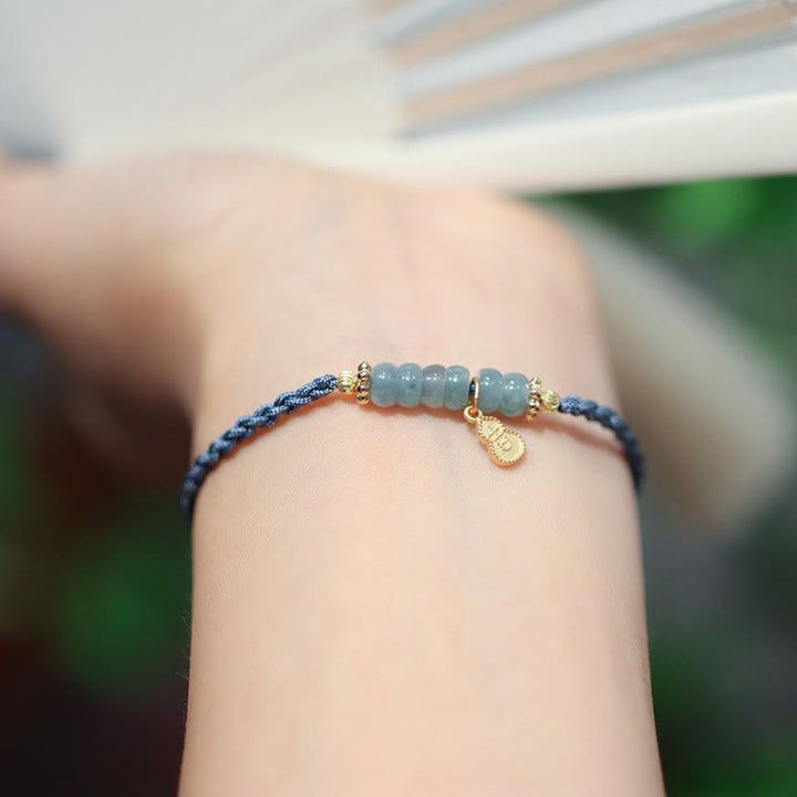 Blaugrünes Jade Armband mit goldenem Charm am Handgelenk getragen