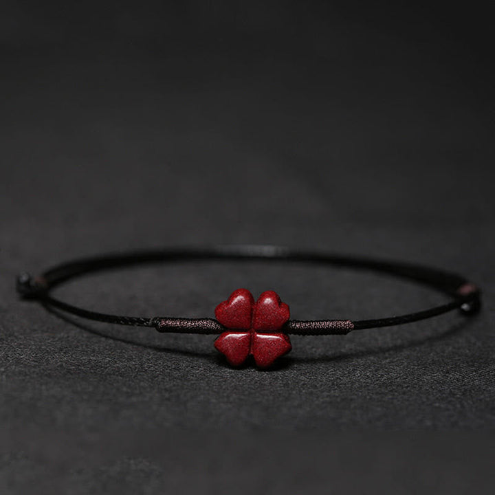 Rotes Armband mit Koi-Fisch-Anhänger auf dunklem Hintergrund, Nahaufnahme.