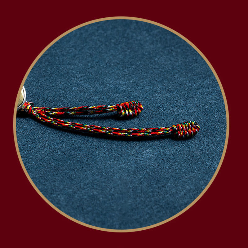 Rotes gelbes schwarzes geflochtenes Armband auf blauem Stoff Hintergrund.