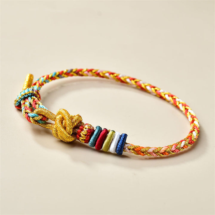 Buntes geflochtenes Armband mit goldenem Knoten und Perlen.