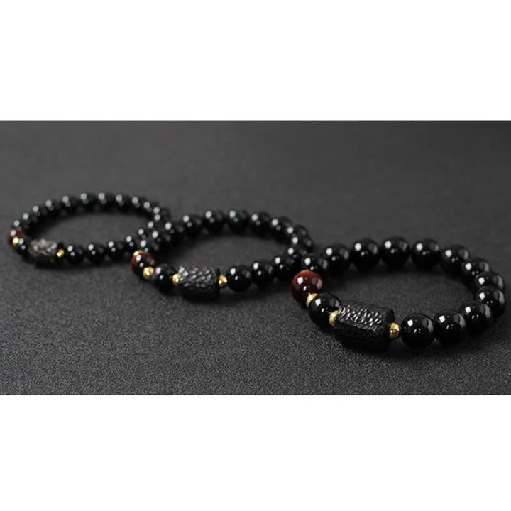 Drei schwarze Obsidian Tigerauge Armbänder mit goldenen Akzenten nebeneinander.