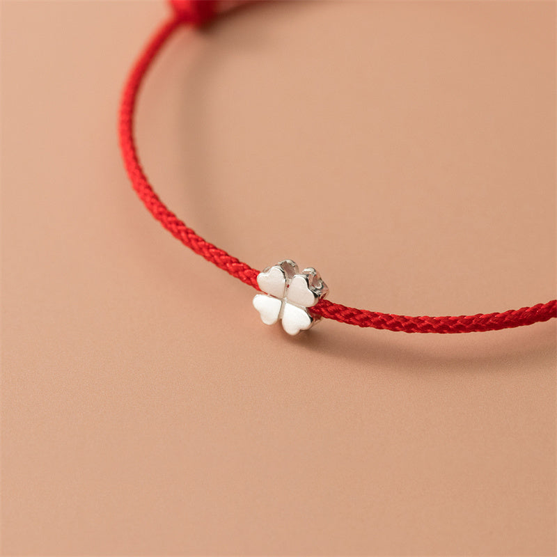 Rotes Armband mit silbernem Kleeblatt Charm elegant am Handgelenk.
