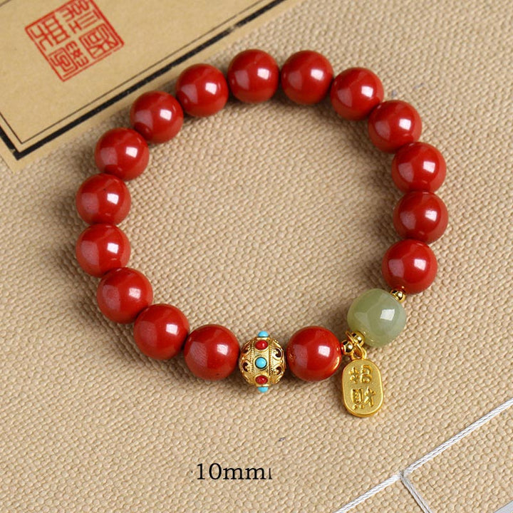 Rotes Armband mit grünem Aventurin Stein auf Stoffhintergrund, Detailaufnahme.
