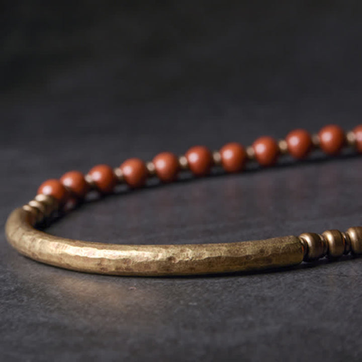 Armband mit roten Perlen und goldenem Rohr auf dunklem Hintergrund Nahaufnahme