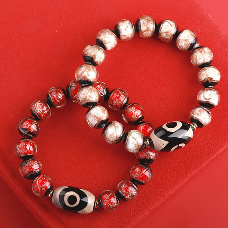 Armband – Wohlstand Balance mit roten und silbernen Perlen auf rot.