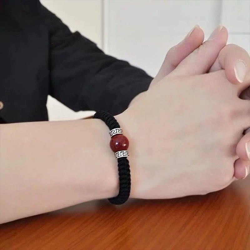 Schwarzes elastisches Armband mit Zinnober Stein und Silber Verschluss.