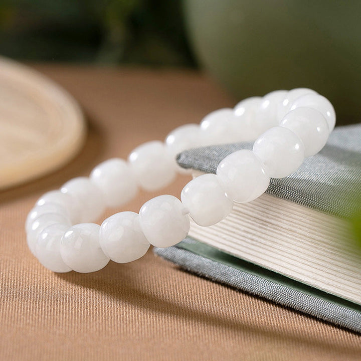 Armband Weiße Jade – Glück & Segen elegant auf Stoff drapiert