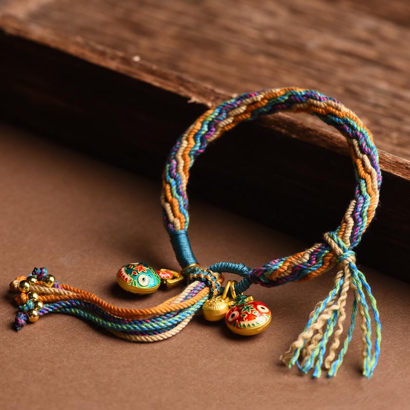 Buntes Armband mit goldenen Glücksbringern auf Holzuntergrund, elastisch.
