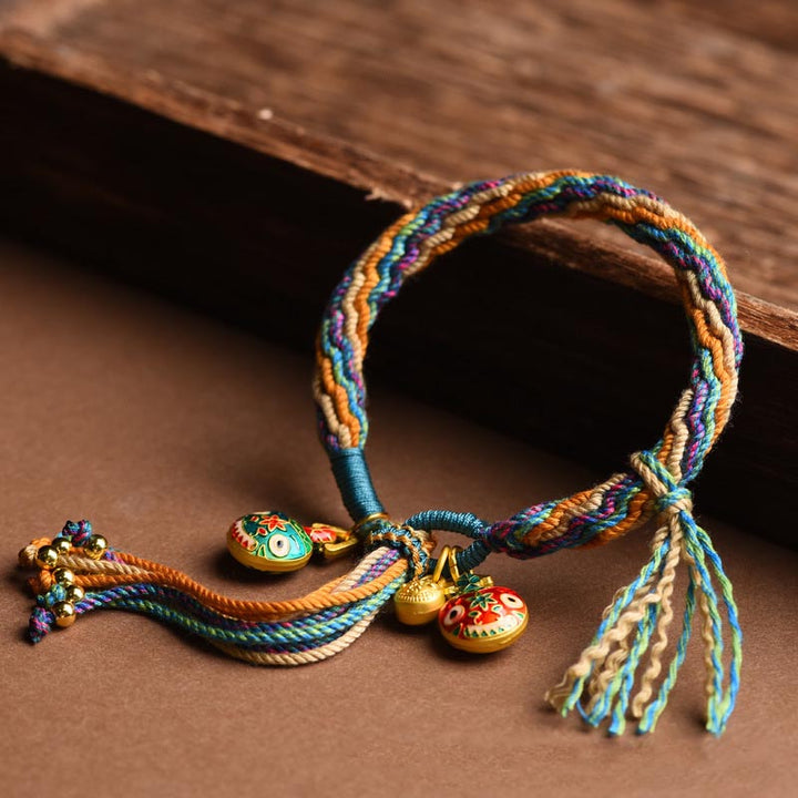 Buntes Armband mit goldenen Glücksbringern auf Holzuntergrund, elastisch.