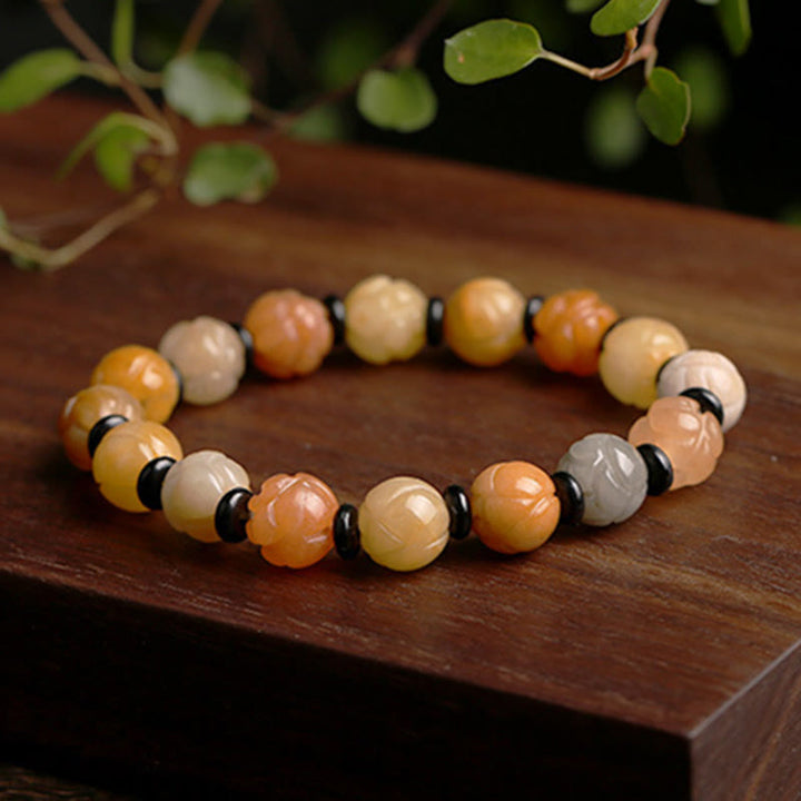 Jade Lotus Armband mit natürlichen Steinen auf Holzoberfläche.