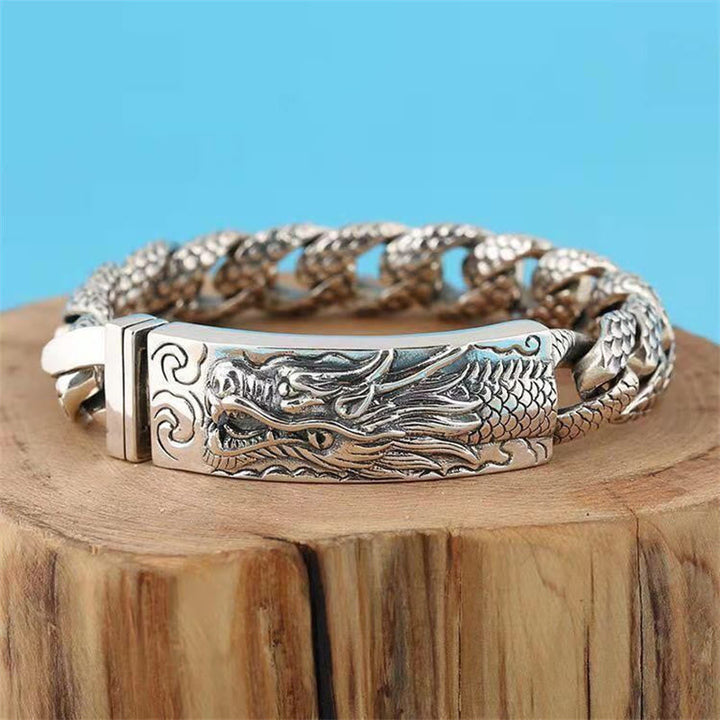Silbernes Drachen Armband mit geflochtener Kette auf Holzblock.