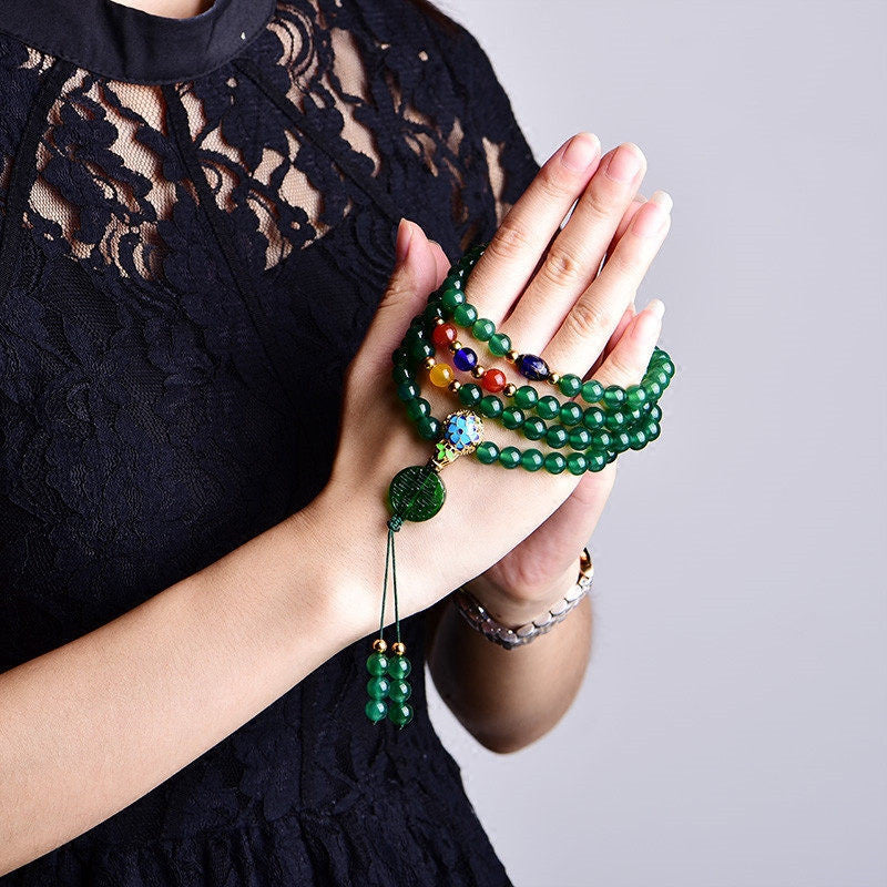 Grüne Mala 108 Perlen Achat Armband an weiblicher Hand getragen.