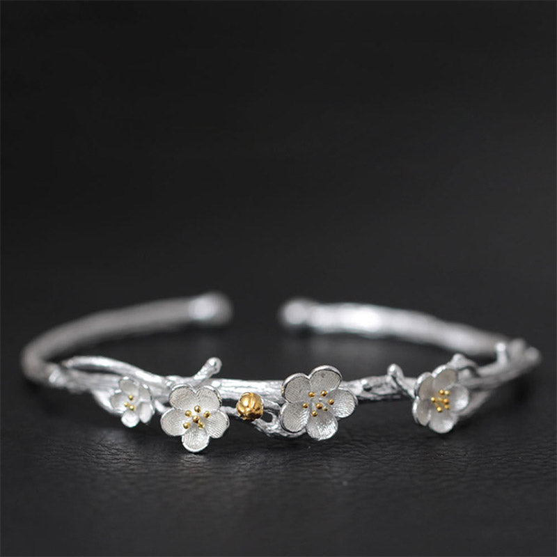 Silberarmband mit Blütenanhängern und goldfarbenem Akzent elegantes Design.