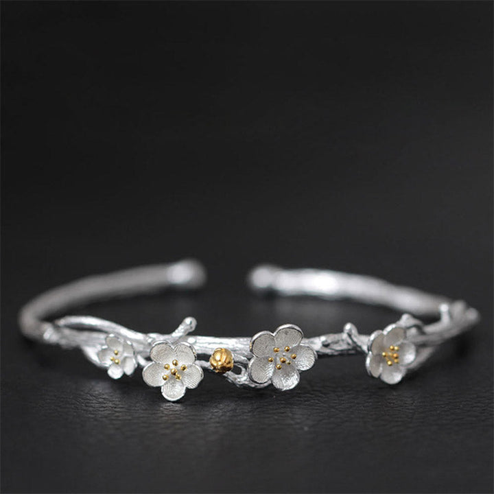 Silberarmband mit Blütenanhängern und goldfarbenem Akzent elegantes Design.