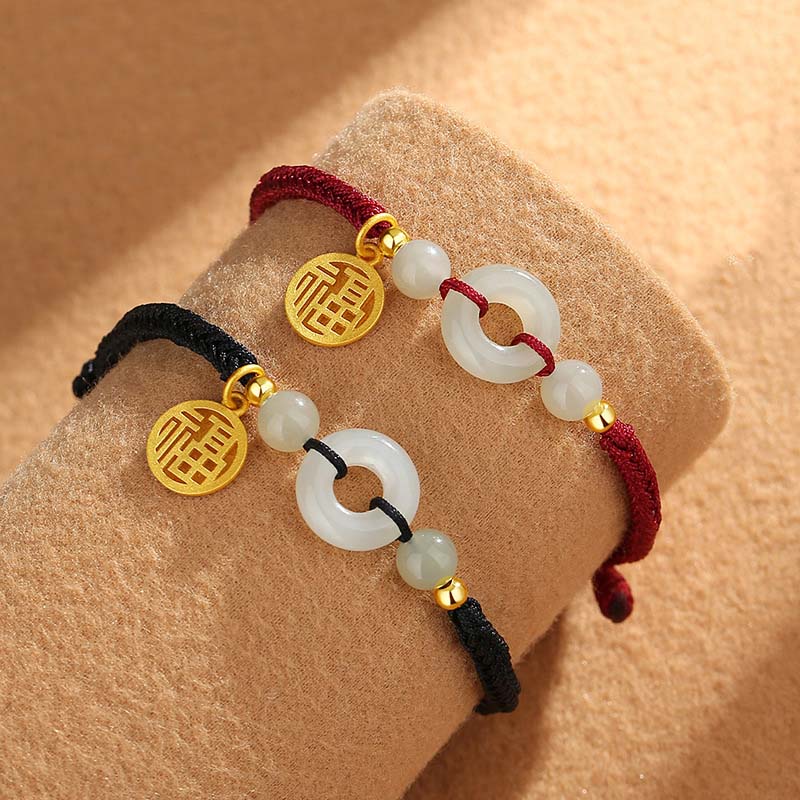Zwei Jade Armbänder mit goldenem Fu-Zeichen Anhänger am Handgelenk.