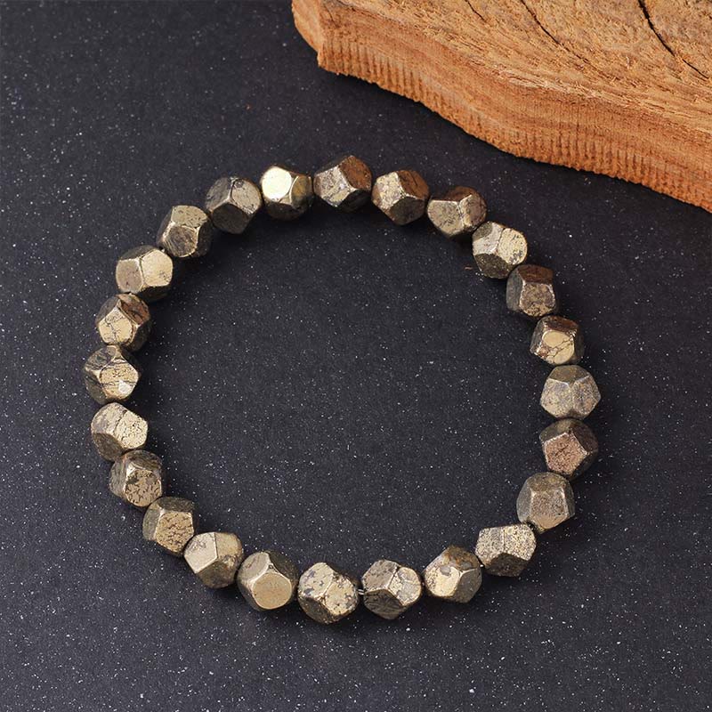 Armband Pyrit Buddha Schutz Vertrauen facettierte Perlen auf dunklem Stein