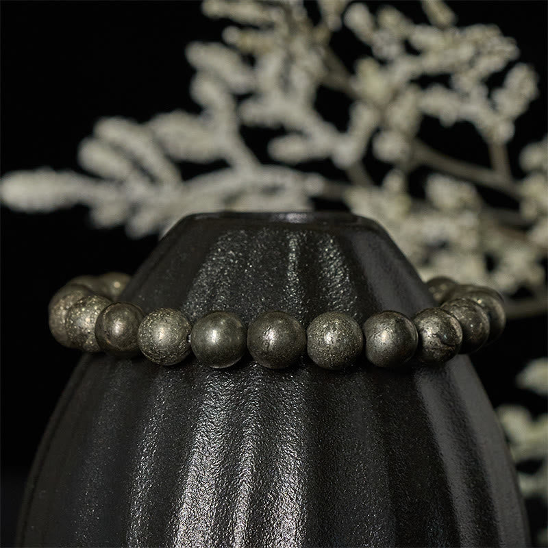 Armband Pyrit Vertrauen Wohlstand Perlen schwarze Vase dekorativer Hintergrund elegant