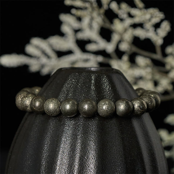 Armband Pyrit Vertrauen Wohlstand Perlen schwarze Vase dekorativer Hintergrund elegant